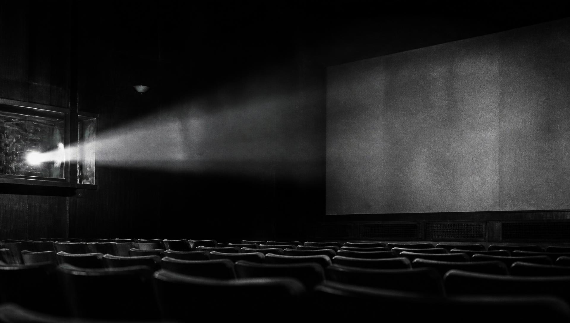 Projector beam cutting through a dark, empty screening room
